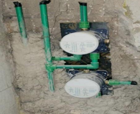 Water meters and pipework installed against a concrete ceiling